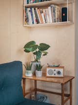 Hanging shelves and a wood side table in the living area provide added storage space for the tiny home.
