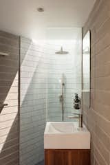 The small bathroom on the first level features concrete block walls and ceramic mosaic tile. A skylight in the shower supplies an indoor/outdoor experience.