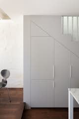 White-painted storage cabinets are built into the wall beneath the staircase.