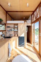 When the shutters are open, the interior of the tiny cabin feels connected to the landscape via the large glass doors in the kitchen area.