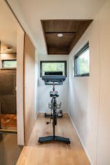 A coffered walnut ceiling in the micro-gym provides the headroom necessary to stand and ride a Peloton bike. The windows in front of (and beside) the bike provide the feeling of riding outdoors.
