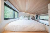 The loft-style bedroom features a headboard with integrated LED lightning for reading in bed at night. Windows on either side of the bed provide cross ventilation.