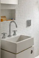 White-painted cabinetry and white mosaic wall and floor tile create a fresh aesthetic for the bathroom.
