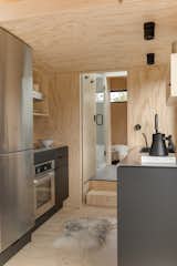 The interior of the micro-cabin is finished with pine plywood that provides pattern and an organic quality. In the kitchen, stainless-steel cabinetry, counters, and appliances lend an industrial aesthetic that balances the materiality of the wood.