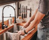Hexagonal ceramic tile on the backsplash and a stainless steel double sink provide a sleek aesthetic for kitchen area.  Photo 5 of 11 in Budget Breakdown: An Architecture Student Turns an Old School Bus Into His Home for $7K