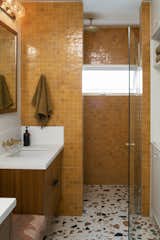 Built-in teak seating is now flanked by custom vanities, with Marmoreal flooring and marigold zellige shower tile.