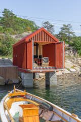 Exterior, Metal Roof Material, Boathouse Building Type, Gable RoofLine, Cabin Building Type, Tiny Home Building Type, and Wood Siding Material A retractable terrace cantilevers over the sea and holds a pair of large double doors open, tying the cabin to the water.  Photo 7 of 9 in This Tiny Boathouse in Norway Is a Private Retreat in Plain Sight from The 20 Most-Liked Homes on Our Instagram in 2023