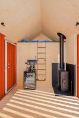 The interior is arranged with a living area, a loft-style sleeping area, and a bathroom that’s accessed from the outside. An Ankarsrum wood stove heats the space.