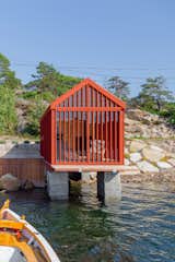 Exterior, Tiny Home Building Type, Boathouse Building Type, Cabin Building Type, Gable RoofLine, Wood Siding Material, and Metal Roof Material A retractable wood terrace slides out from beneath the tiny cabin and is stowed when not in use.  Photo 2 of 9 in This Tiny Boathouse in Norway Is a Private Retreat in Plain Sight
