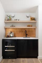 The wet bar features a backsplash covered with copper-colored glass tile. The lower cabinets are shou sugi ban–treated red oak, and the open shelves are made of white oak.