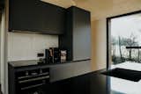The charcoal-colored cabinetry and quarts counters contrast with the pale wood walls and ceiling, providing a fresh aesthetic for the interior.