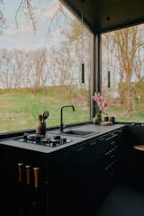 In the kitchen, large windows frame views of the nearby forest and meadows.