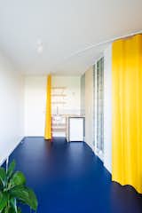 Kitchen, Wood Counter, Wall Mount Sink, Cooktops, Drop In Sink, Refrigerator, Linoleum Floor, Wall Lighting, Marble Backsplashe, and Ceiling Lighting Miogui architecture filled this 141-square-foot studio apartment in Normandy with bold color and playful geometric forms.
