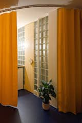 In the evening, the yellow tone of the curtain bounces off of the glass-block wall and creates a warm glow for the apartment.