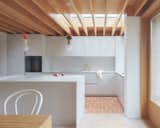 Terracotta tile flooring in the kitchen is juxtaposed with Douglas fir flooring in the dining area. A skylight facilitates the inflow of natural light for the spaces.