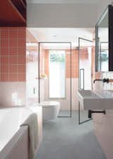 The daughters' bathroom showcases pink tile in two shades and concrete flooring.