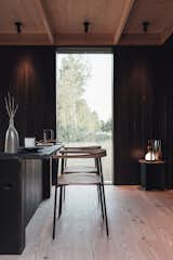 Dining Room, Chair, Table Lighting, Table, Light Hardwood Floor, Bar, and Lamps The modular cabin's dining area showcases a built-in bar area flooded with natural light by an adjacent floor-to-ceiling window.  Photo 4 of 11 in These Tiny Prefab Cabins Are Designed to Feel Like Luxe Hotel Rooms from A Svelte $79K Prefab Cabin Promises to Work as Well in Your Backyard as It Does in the Woods