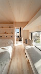 The bedroom features a large picture window and built-in shelving and seating.