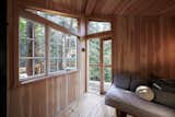 Numerous windows connect the interior of the tree house to its wooded landscape.