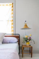 Drapery fabric with a bright yellow polkadot print, flowers from the backyard garden, and a vintage-style metal light fixture enliven the guest room.  Photo 11 of 14 in Meet the Women Who Reimagined a Hudson Valley Farmhouse as a BIPOC Residency