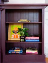 Built-in shelves painted with a deep-magenta tone by Farrow &amp; Ball showcase books by a number of Black authors including Samantha Irby, Alice Walker, and Zadie Smith.