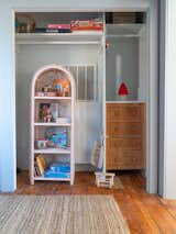 A woven bookshelf is arranged with a curated selection of children’s games and books, such as Hair Love by Matthew A. Cherry and Saturday by Oge Mora. The toys are from Brimful.