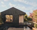 The suburban backyard garage in Hertfordshire, England, that architect Olli Andrew of Hyper converted into a work studio is wrapped in charred larch wood pieces that give the impression of scales and foster biodiversity, providing a place for insects to nestle.