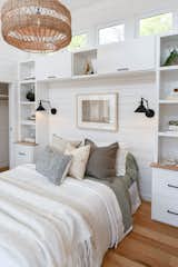 Built-in shelving and cabinetry frames the bed in the bedroom  Photo 9 of 13 in Budget Breakdown: A $237K Tiny Home on Wheels Brings Kids, Parents, and Their Parents Together