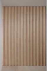 A ribbed wall made from maple features a hidden door that accesses the primary bedroom, which is located just off the entry.
