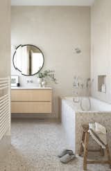 Neutral terrazzo flooring and plaster walls offer interest and texture in the upper level bath.