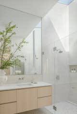 A skylight in the primary bath harnesses abundant sunlight for the space and gives the feeling of being outdoors. White Caesarstone quartz counters top pale maple cabinetry, lending a serene quality.