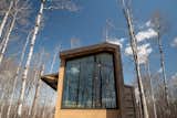 The steel-and-glass wrapped 300-square-foot tiny house that Fritz Tiny Homes designed for Refuge Bay Luxury Camping eco resort in Alberta, Canada, connects to its wooded landscape, providing a feeling of being outdoors while relaxing on the interior.