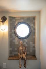 A Joe Brubaker sculpter perches in the guest bathroom, where the design team arranged a caged sconce that references old ships. The tile is by  the historic Heath Ceramics, which is located in Sausalito.