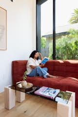 Jyotsna reads on a custom sofa by Retro Modern Design, Vancouver B.C., Canada, in the living area.