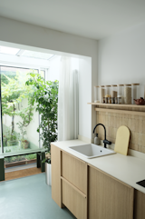 Green linoleum flooring in the kitchen connects the room to the greenery-filled courtyard.