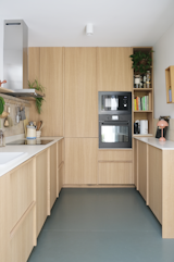 Oak cabinetry and reclaimed Corian counters provide rich textures in the sunlight-filled kitchen.