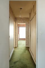 Before the redesign, the hallway showcased green carpet and floral wallpaper.
