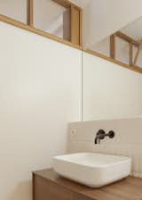 White walls and white textured tile offset an oak vanity in one of the bathrooms.