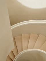 The oculus reflects a ring of sunlight on the clay plaster wall that partially wraps the staircase.