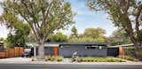 The 1950 Eichler home in Palo Alto, California, that Ogawa Fisher Architects renovated for a family of five features a cool gray facade punctuated by a bright orange front door.