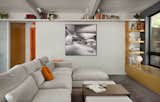 The open-plan living area is outfitted with a sectional, large format porcelain tile flooring, and an integrated oak storage bench and shelving.