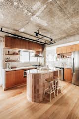 The kitchen showcases Freijó wood cabinetry, marble counters, and an oval-shaped island covered in pink ceramic tile with a glossy finish from Portobello America.
