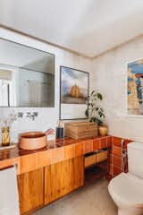 Freijó wood cabinetry topped with large-format terracotta-colored ceramic tile from Portobello America in one of the bathrooms. The concrete sink is from <span style="font-family: Theinhardt, -apple-system, BlinkMacSystemFont, &quot;Segoe UI&quot;, Roboto, Oxygen-Sans, Ubuntu, Cantarell, &quot;Helvetica Neue&quot;, sans-serif;">Konkrë Living Design.</span>