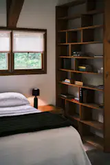 Wood trim, a large wood bookshelf, and a vintage wood accent table offer warmth and texture in the upper-level bedroom.
