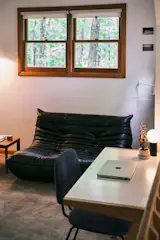 <span style="font-family: Theinhardt, -apple-system, BlinkMacSystemFont, "Segoe UI", Roboto, Oxygen-Sans, Ubuntu, Cantarell, "Helvetica Neue", sans-serif;">A black leather-upholstered sofa, inspired by the Togo sofa by Michel Ducaroy for Ligne Roset, supplies a chic, casual aesthetic for the loft area.</span>