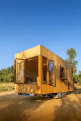 A corner window in the living room pivots open and links the interior with the surrounding landscape. "A foldable table on the exterior aligns with the kitchen window, connecting the kitchen to the outdoors and encouraging open-air dining and socializing,