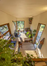 A raised living space with integrated storage is open to the kitchen-and-dining area, where there's birch plywood cabinetry and Thermowood counters.