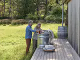 "The clients embraced a more rustic approach with a portable outdoor tub and a makeshift tree-side shower because it aligned with their values and minimized plumbing complexity,