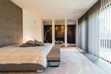 Bedroom, Medium Hardwood Floor, Table Lighting, Ceiling Lighting, Rug Floor, Bed, and Bench  Photo 3 of 6 in Prestigious Modern Villa in Belgium Asks $6.8M by Sotheby’s International Realty