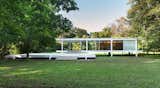 Farnsworth House by Ludwig Mies van der Rohe: Midcentury style house white exterior with flat roofline and glass siding in landscape with grass and trees